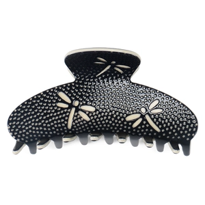 Detail of premium acetate hair claw with dragonfly motifs and textured surface finish