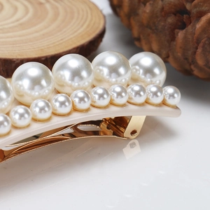 Détails des perles nacrées sur une pince à cheveux avec clip doré et base beige