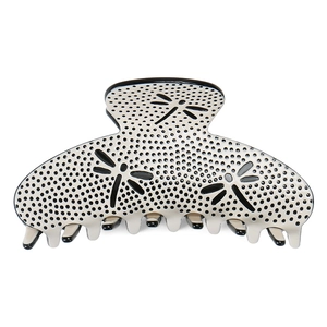 Macro detail of glossy acetate hair claw clip featuring chic dragonfly patterns and polka dots