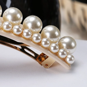 Vue détaillée d'une élégante barrette dorée ornée de perles de culture superposées