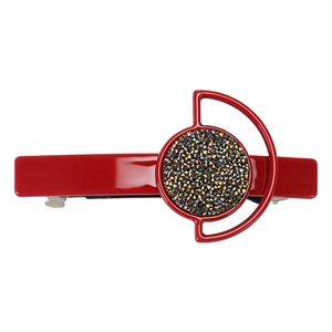 Macro detail of red vintage hair clip with embedded rhinestones on a glossy surface