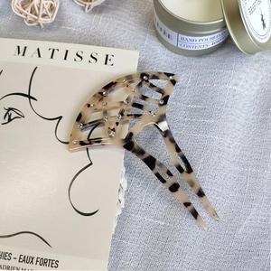 Detailed view of tortoiseshell fan-shaped hair comb with rhinestones on linen background