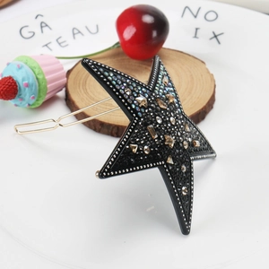Détail du clip à cheveux étoile noire orné de strass colorés et fermoir métallique doré