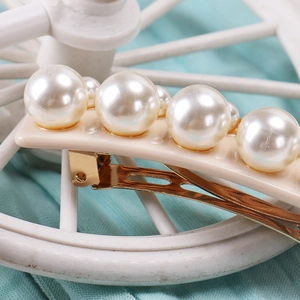 Détail des grandes perles sur pince à cheveux dorée avec une base en résine crème