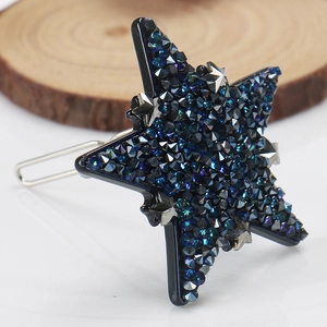 Détail d'une pince à cheveux en forme d'étoile avec strass bleus sur base acétate