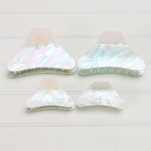 Detail view of large and small Mount Fuji acrylic hair claws with pearly marble texture