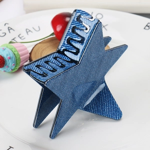 Détail d'une pince à cheveux étoile en jean bleu sur un plateau en céramique