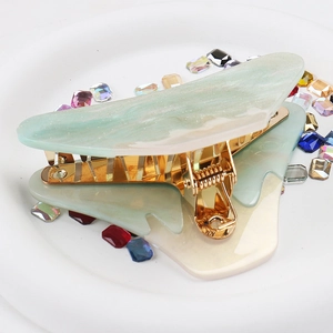 Close-up of mint green marble acrylic hair claw clip with golden metal base