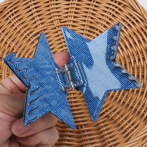 Vue détaillée de la pince à cheveux étoile en denim avec mécanisme à ressort doré