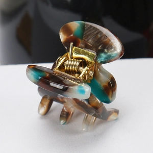 Macro detail of tortoiseshell acetate hair claw clip with a strong golden metal spring