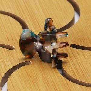 Macro shot of a mini tortoiseshell hair claw clip with marble texture on a wooden surface