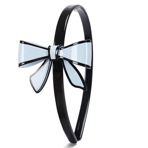 Dettaglio di un cerchietto in acetato nero con fiocco a contrasto blu e nero lucido