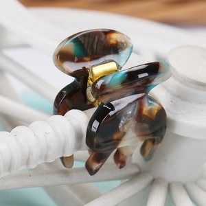 Close-up of small acetate hair claw with blue amber marble pattern and gold spring