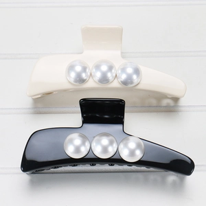 Detail of large black and cream acetate hair claws with three elegant faux pearls