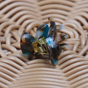 Detail view of mini acetate hair claw with tortoiseshell pattern and gold metal spring