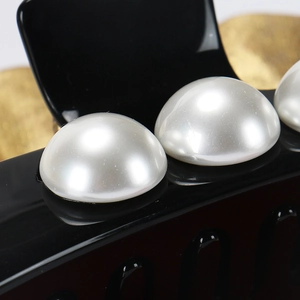 Detail of glossy black hair claw clip featuring three large elegant white faux pearls