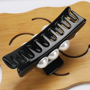 Detailed view of large black acetate hair claw clip with elegant faux pearl accents