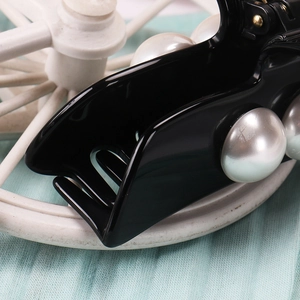 Macro shot of large black acetic hair claw clip featuring elegant oversized white pearls