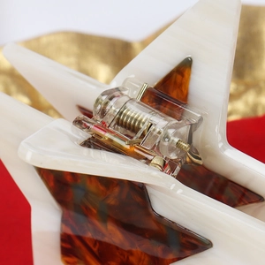 Macro detail of star-shaped hair claw clip showing polished acetate texture and spring mechanism