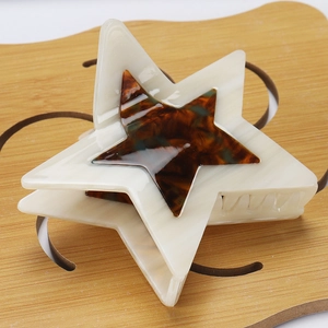 Detail of star-shaped hair claw clip in cream marble and dark tortoiseshell acetate