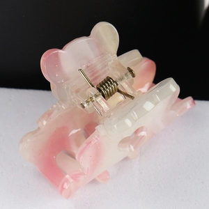 Close-up of pink marble acrylic hair claw with cute bear ears and heart detail