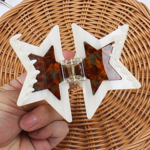 Detail of a large double-layer star hair claw clip with tortoise shell and cream patterns