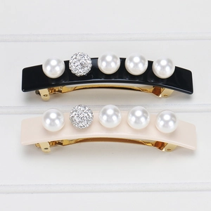 Detail showing pearl and rhinestone acetate hair clips with golden metal spring clamps