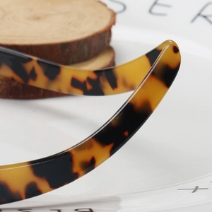 Detail of tortoise shell acetate headband with polished finish on a wooden background