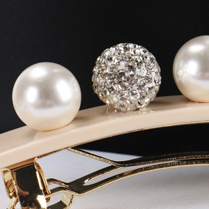 Macro view of cream acetate hair clip with white faux pearls and sparkling rhinestone ball