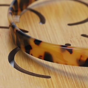 Macro shot of tortoiseshell acetate headband with anti-slip teeth on a wooden surface
