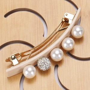 Close-up of elegant acetate hair clip with pearls and sparkling rhinestones on gold metal clip