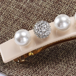 Macro detail of acetate spring clip with white pearls and sparkling rhinestone sphere decoration