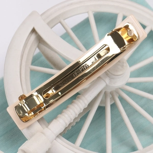 Detail view of the sleek cream resin surface and golden metal spring clip mechanism