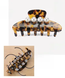 Detailed close-up of large acetate tortoiseshell hair claw clip with four white pearls