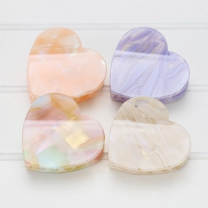 Nahaufnahme von vier herzförmigen Acetat-Haarklammern in pastellfarbenem Marmordesign