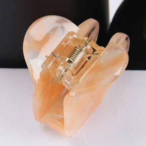 Makroaufnahme der pfirsichfarbenen Haarspange aus Acetat mit goldener Metallfeder