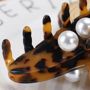 Close-up of tortoise shell acetate hair claw with elegant white pearl embellishments