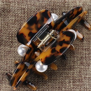 Detail of tortoiseshell acetate hair claw clip featuring four large glossy white pearls