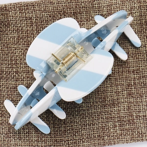 Close-up of a large blue and white striped acetate hair claw clip with a metal spring
