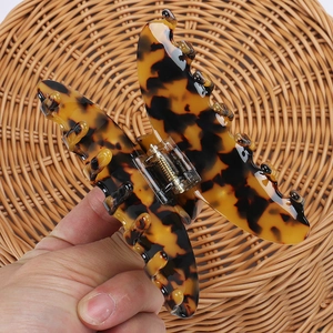 Detail of tortoiseshell acetate hair claw clip showing glossy texture and golden spring