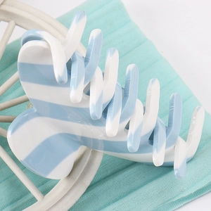 Detail shot of striped acetate hair claw clip with blue and white pattern texture