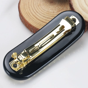 Detail view of the black acetate hair clip with golden alloy spring closure and elegant finish