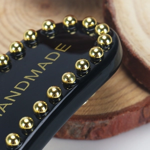 Macro shot of black handmade acetate hair clip with gold metal beads and engraving