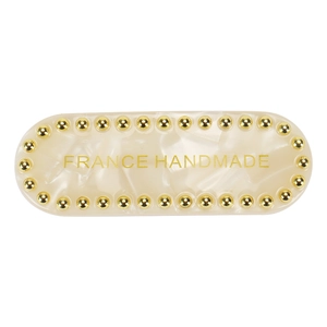 Detail view of cream acetate hair clip with gold studs and France Handmade text