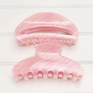 Detail of pink marble acrylic hair claw clip with gold glitter on white wood background