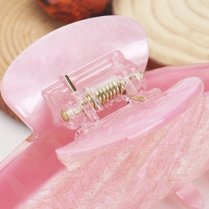 Detail of pink glitter acrylic hair claw clip showing the reinforced golden metal spring