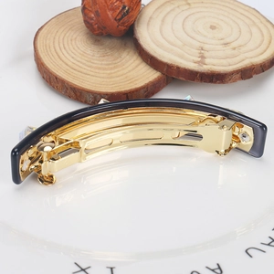 Detail der grauen Acetat-Haarklammer mit glitzernden Kristallen auf goldener Metallbasis