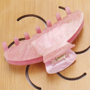 Close-up of pink glitter acrylic hair claw clip with marble texture and metal spring