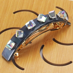 Makroaufnahme einer Haarspange mit Marmortextur und Kristallen auf goldener Metallbasis