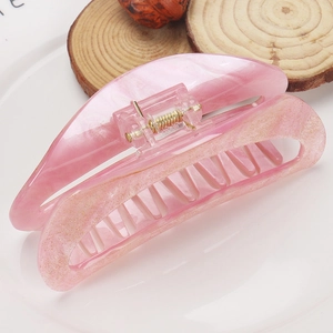 Detail of pink marble glitter acrylic hair claw clip with golden metal spring mechanism